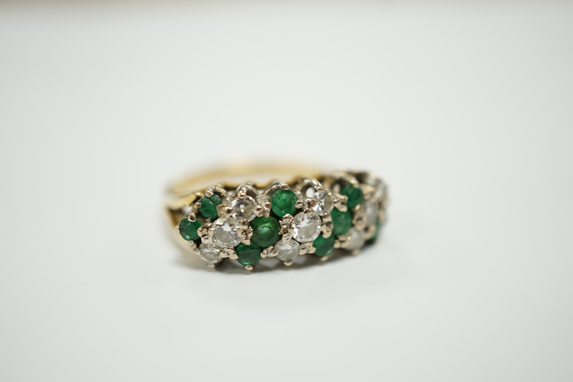 A modern 18ct, emerald and diamond set cluster half hoop ring, size O, gross weight 4.9 grams.